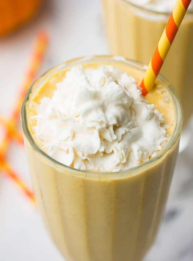 close up of top of pumpkin milkshake with whipped cream and colorful straw