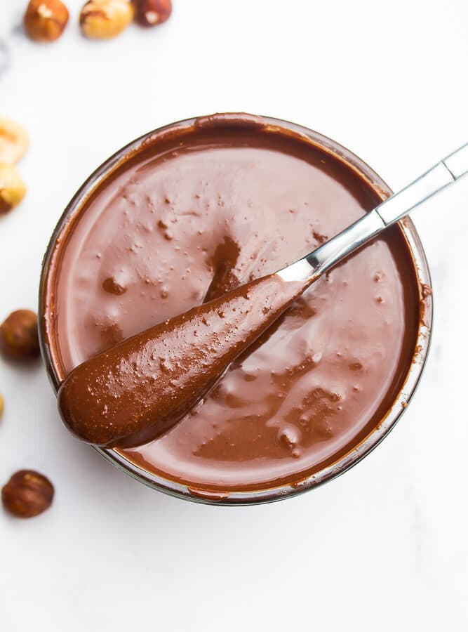 vegan nutella on a knife, sitting on a glass bowl.