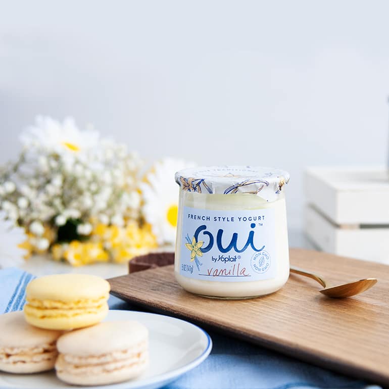 Vanilla Oui by Yoplait Yogurt ready to be served next to three french macarons.