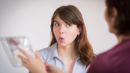 Frau macht zusammen mit einer Logop&auml;din Sprachübungen