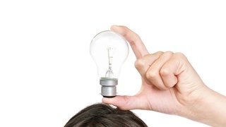 Eine Frau h&auml;lt eine Glühbirne über ihren Kopf.