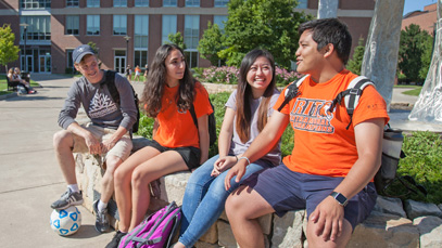 4 students sit on rock wall