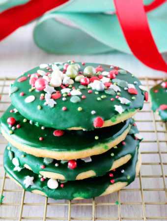 A stack of iced sugar cookies on a cooling rack with ribbon in the background.