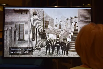 Bessie Kourkoulakos watches a video slideshow of historical pictures